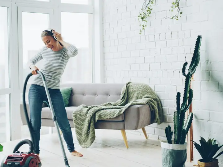 Cleaner vacuuming a bright living room